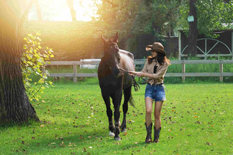 户外草地上青年女人牵着马