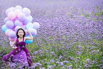 拿着气球的小女孩在花海里奔跑