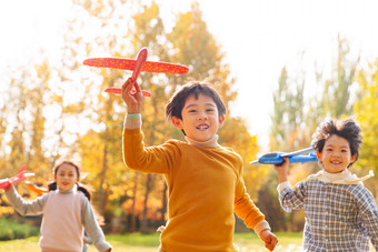 拿着玩具飞机在公园玩耍的快乐儿童