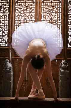 青年女人在中式古典门前跳芭蕾舞