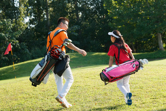 球场上教练和学生背着高尔夫球包行走