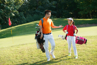 球场上教练和学生背着高尔夫球包交谈