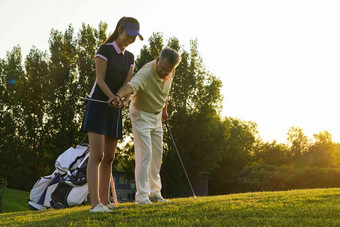 青年人女人和老年人打高尔夫