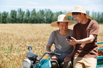 农民坐在三轮车上使用手机