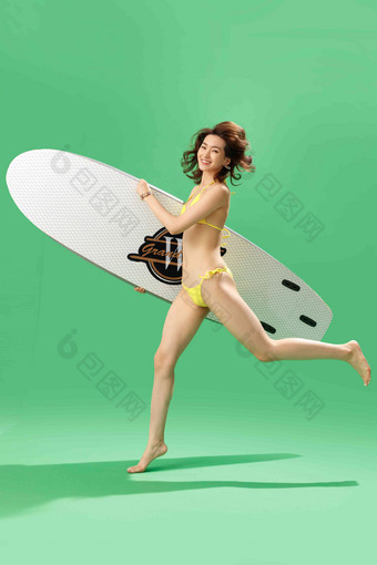 兴奋的青年女人抱着冲浪板奔跑