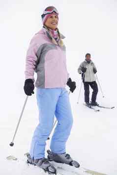 女人滑雪站滑雪坡男人。滑雪板背景