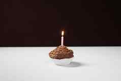 美味的巧克力蛋糕点燃生日蜡烛表格孤立的黑色的背景