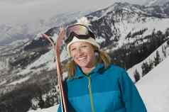 肖像快乐的女滑雪持有滑雪板山