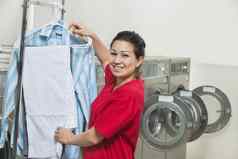 肖像快乐年轻的女人干燥衣服自助洗衣店