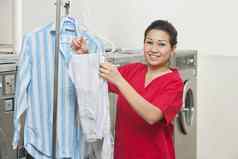 肖像快乐年轻的女人衬衫挂自助洗衣店