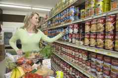 成熟的女人选择罐头货物超市过道