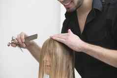 男人。切割梳理年轻的女士头发理发师