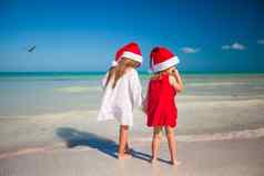后视图可爱的女孩圣诞节帽子异国情调的海滩
