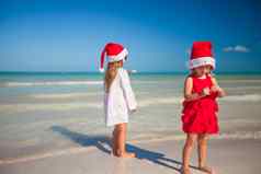 可爱的女孩圣诞节帽子异国情调的海滩