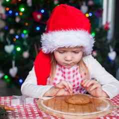 可爱的女孩圣诞老人他吃面团姜饼干