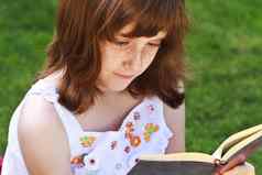 年轻的美丽的女孩阅读书户外