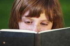 研究年轻的美丽的女孩阅读书户外