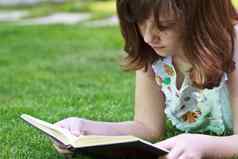 研究年轻的美丽的女孩阅读书户外