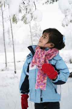 女孩站雪覆盖树冬天