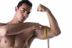 肌肉发达的赤膊上阵年轻的男人。测量手臂磁带测量