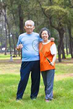 微笑高级夫妇持有羽毛球球拍公园