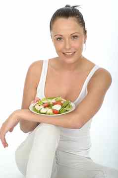 健康的年轻的女人持有板鸡沙拉