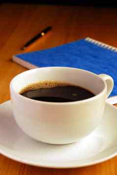 黑色的咖啡橡木桌子上笔记本笔背景