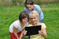 家庭坐着草坪上数字平板电脑