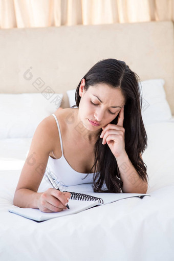 漂亮的浅黑肤色的女人写作床上
