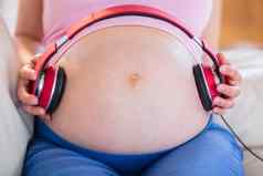 怀孕了女人把耳机肚子