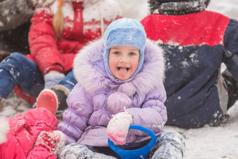 五年女孩坐着雪包围孩子们