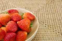 新鲜的草莓木碗柳条制品背景