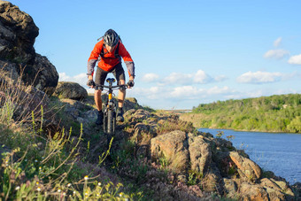 骑自行车的人红色的夹克骑山自行车美丽的春天岩石小道河极端的体育运动概念