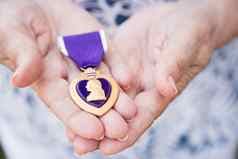 高级女人持有军事紫色的心金牌手