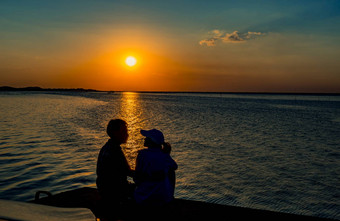 轮廓幸福夫妇爱坐着接吻海滩橙色蓝色的天空日落<strong>夏天</strong>假期旅行概念浪漫的年轻的夫妇<strong>约会</strong>海边