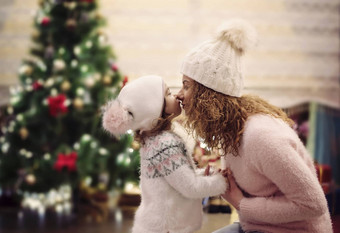 快乐圣诞节快乐假期概念快乐的妈妈可爱的女儿有趣的舒适的装饰生活房间圣诞节树妈妈。接吻拥抱女孩