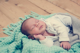 周新生儿婴儿男孩绿色毯子木背景