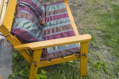 手工制作的木椅子覆盖纺织毯子勃艮第枕头站草花园阳光明媚的夏天一天
