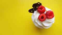 自制的松饼甜蜜的奶油新鲜的红色的树莓黄色的背景