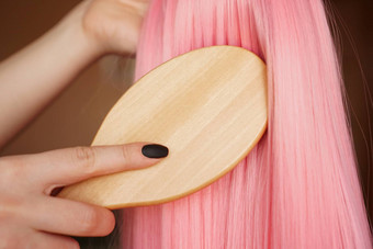 女手持有粉红色的假发长头发库姆斯木梳子