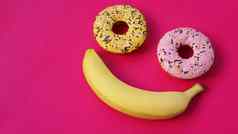甜甜圈香蕉谎言粉红色的表面形成微笑情感
