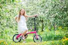 可爱的女孩骑自行车美丽的夏天一天在户外
