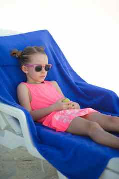 可爱的女孩坐着椅子热带海滩