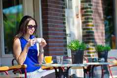 美丽的女人坐着在户外咖啡馆欧洲城市早餐