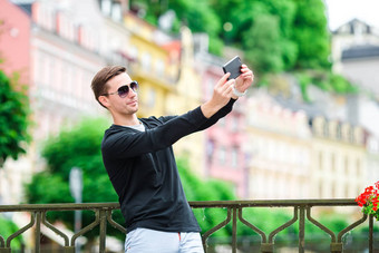 旅游男人。采取旅行照片智能手机夏天假期年轻的有吸引力的旅游采取自拍照片移动电话在户外享受假期旅行目的地旅游