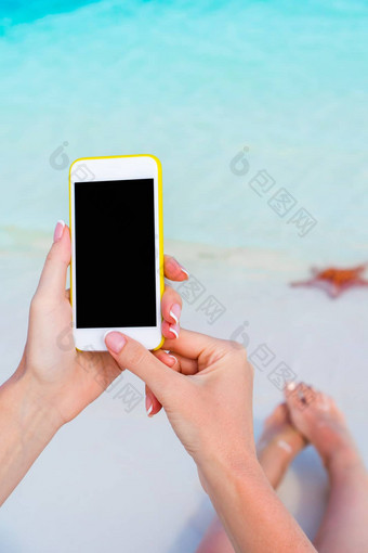 特写镜头智能手机女手背景绿松石海洋热带海滩