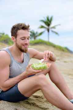 健康的适合男人。素食主义者饮食吃有机食物海滩肌肉发达的年轻的健身的家伙锻炼吃外卖食物准备新鲜的沙拉蔬菜