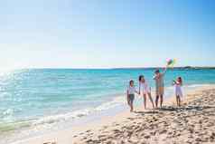 快乐年轻的家庭孩子们飞行风筝海滩