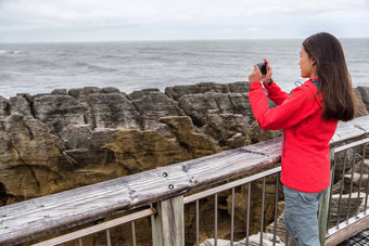 <strong>新西兰</strong>旅行旅游女孩采取智能手机图片电话应用程序红色分配煎饼岩石女人paparoa国家公园西海岸南岛<strong>新西兰</strong>
