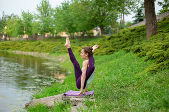 年轻的体育女孩实践瑜伽绿色草坪上河瑜伽阿三的姿势冥想团结自然